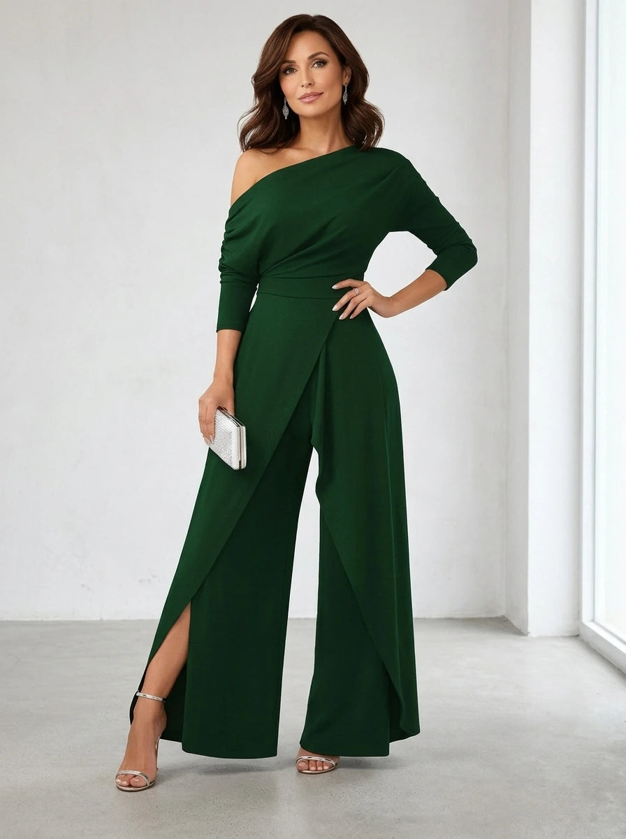 Driftly green asymmetrical one-shoulder jumpsuit with crossed detail and flowing wide-leg trousers, in a minimalist studio setting with soft window light.