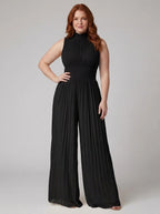 Woman wearing a black pleated sleeveless jumpsuit with structured collar and front zip, studio shot