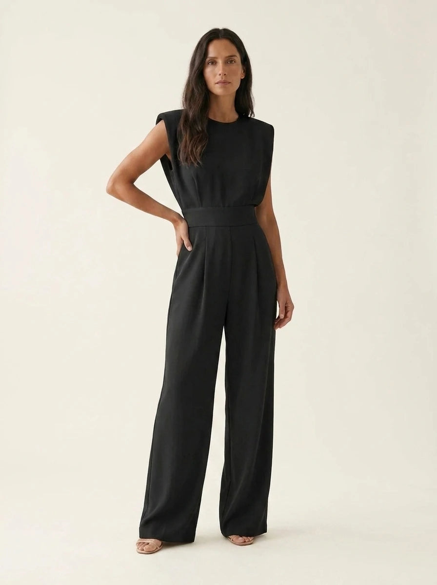 Woman wearing a black sculptural straight-leg jumpsuit with padded shoulders, studio shot