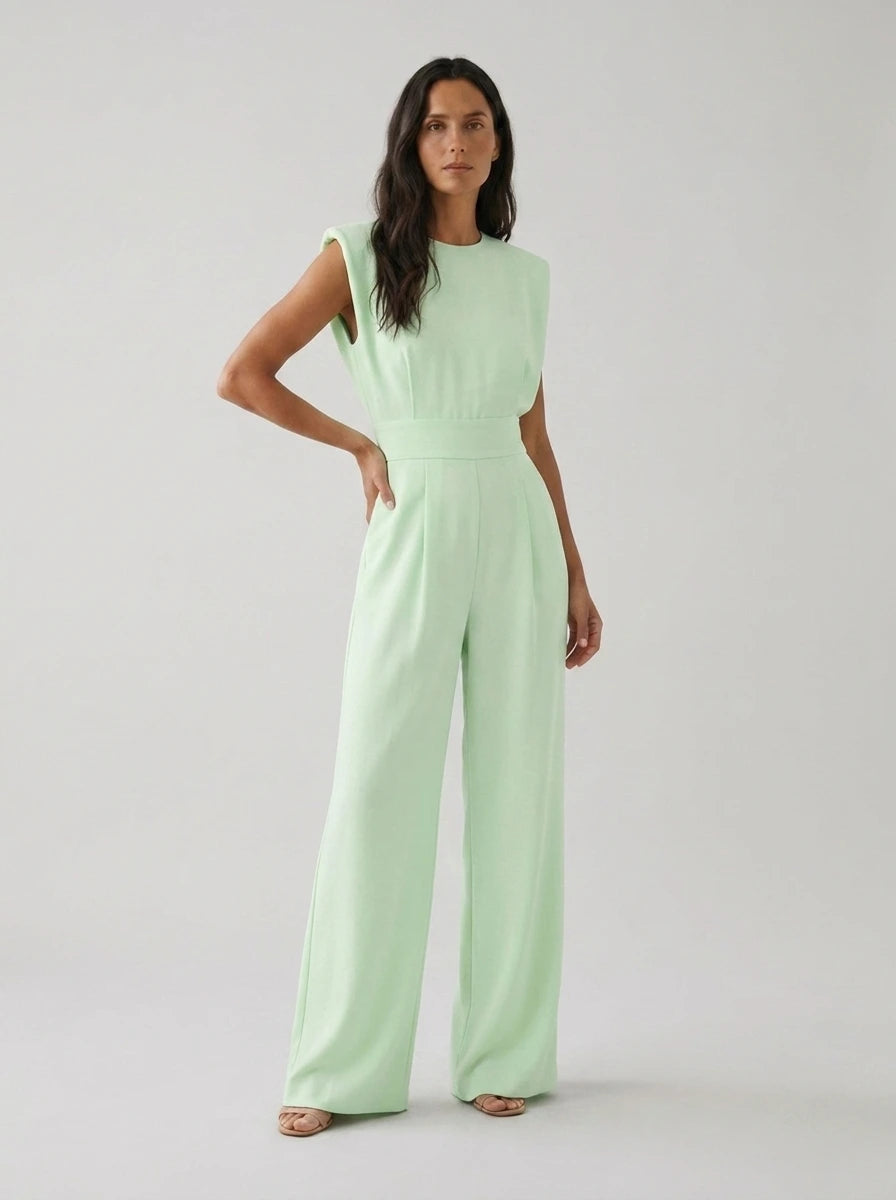 Woman wearing a light green sculptural straight-leg jumpsuit with padded shoulders, studio shot