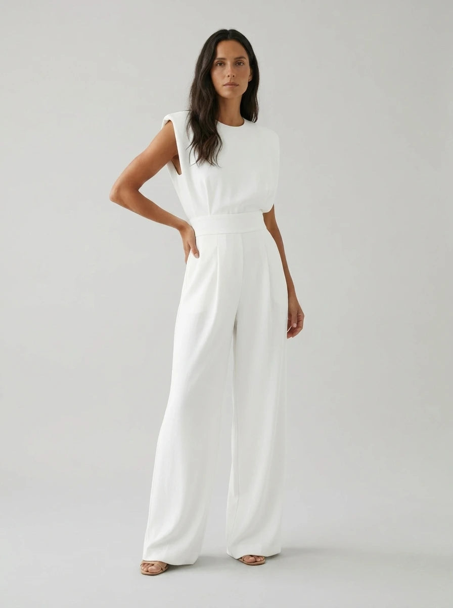 Woman wearing a white sculptural straight-leg jumpsuit with padded shoulders, studio shot