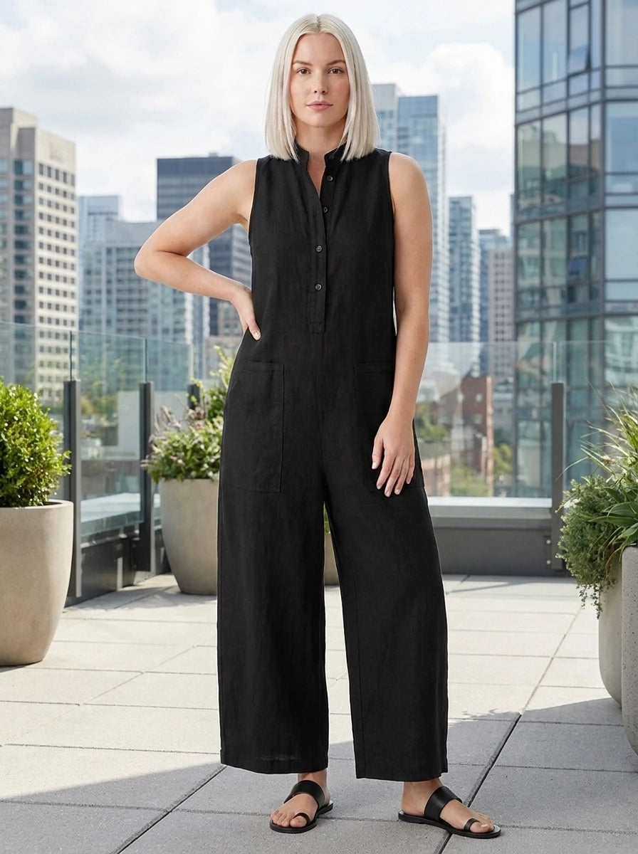 Woman wearing a black sleeveless minimalist jumpsuit on a rooftop terrace with city skyline