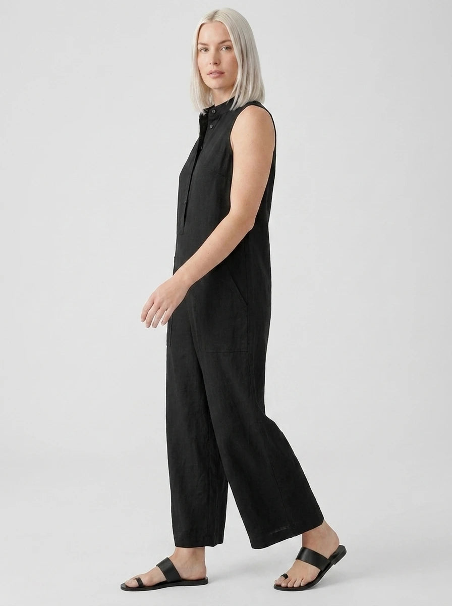 Side view of woman wearing a black sleeveless minimalist jumpsuit, studio shot