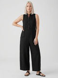 Woman wearing a black sleeveless minimalist jumpsuit with structured collar, studio shot