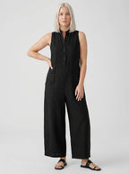Woman wearing a black sleeveless minimalist jumpsuit with structured collar, studio shot