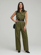 Woman wearing an olive sleeveless utility jumpsuit with black belt, studio shot