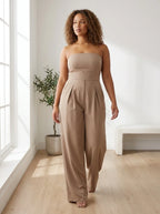 Woman wearing a beige strapless wide-leg jumpsuit in a bright minimalist interior