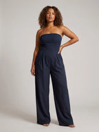 Woman wearing a dark blue strapless wide-leg jumpsuit with fitted top, studio shot