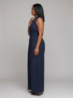 Side view of woman wearing a dark blue striped wide-leg jumpsuit, studio shot