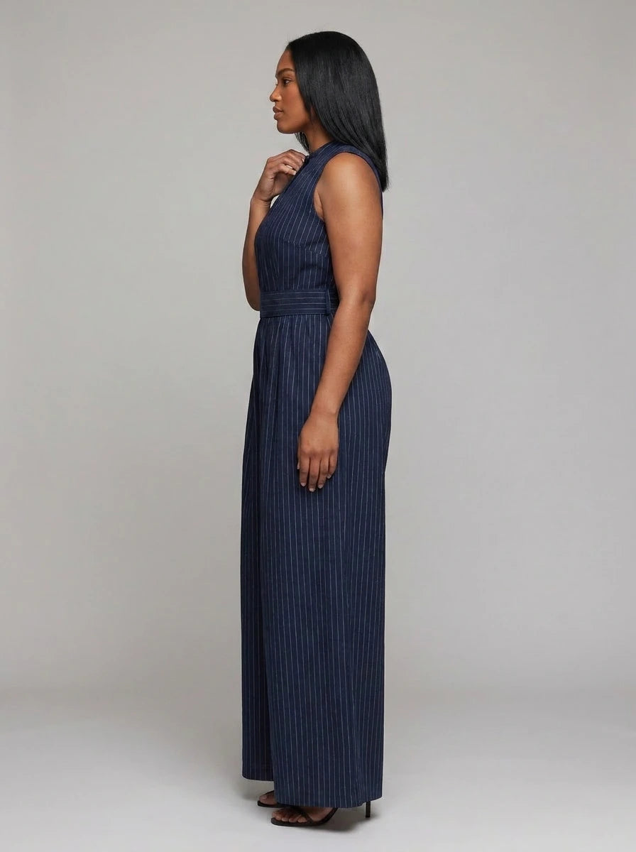 Side view of woman wearing a dark blue striped wide-leg jumpsuit, studio shot
