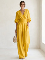 Driftly yellow deep V-neck jumpsuit with relaxed short sleeves, ruched waist, and fluid wide-leg trousers, in a minimalist studio setting with soft window light.
