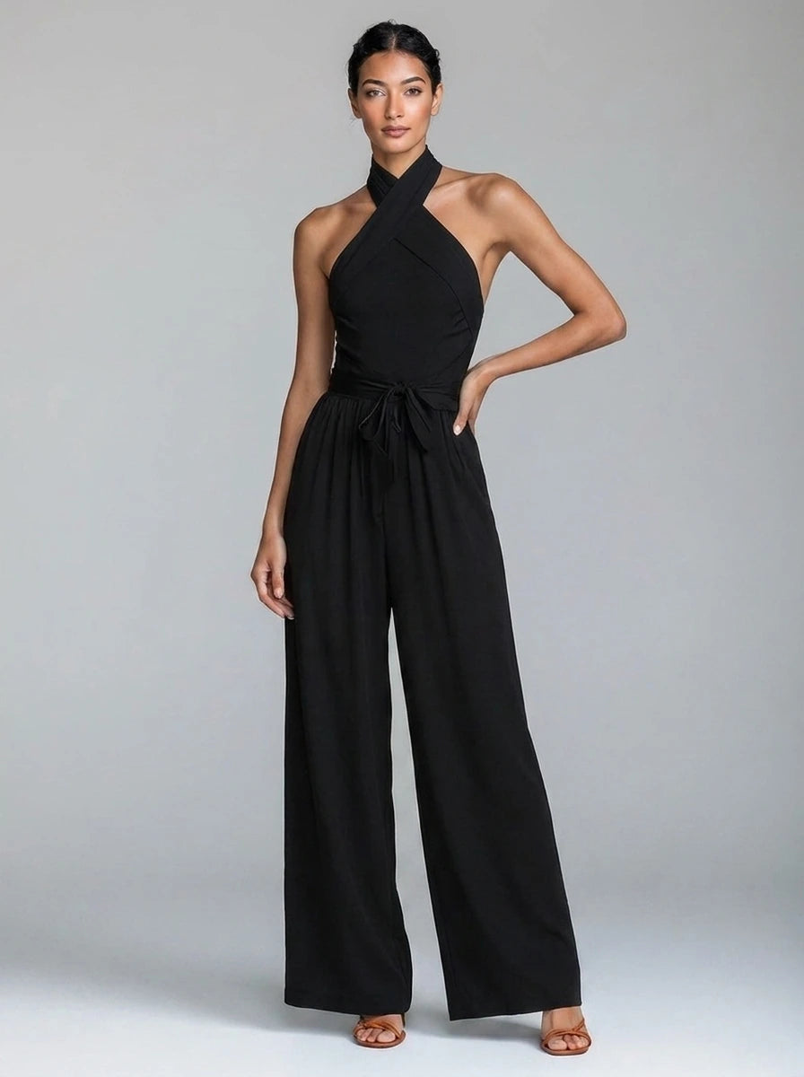 Woman wearing a black wide-leg halter jumpsuit with tie waist, studio shot