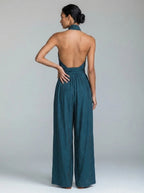 Back view of woman wearing a teal blue wide-leg halter jumpsuit showing open back detail