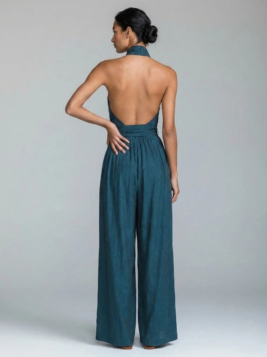 Back view of woman wearing a teal blue wide-leg halter jumpsuit showing open back detail