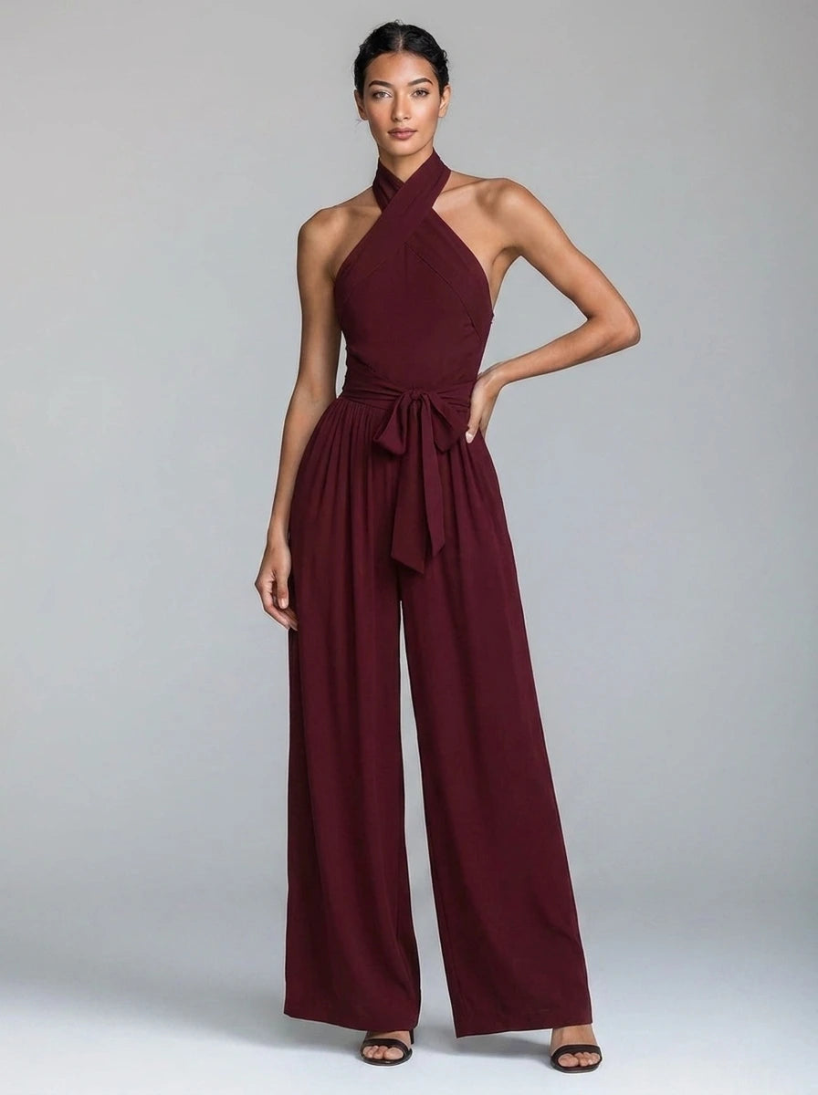 Woman wearing a burgundy red wide-leg halter jumpsuit with tie waist, studio shot