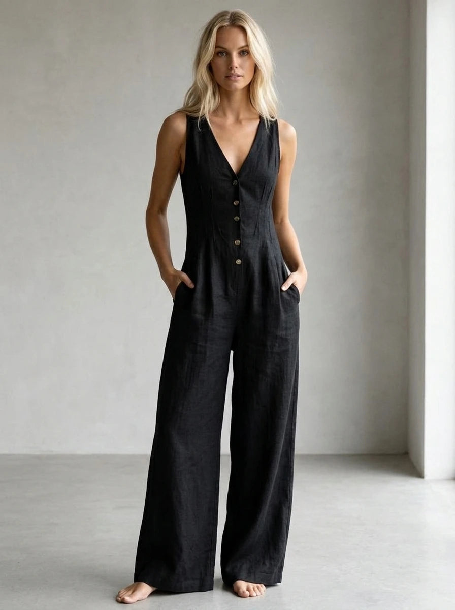 Driftly black V-neck wide-leg jumpsuit with front button closure and side pockets, linen-effect fabric, in a minimalist studio setting with soft window light.