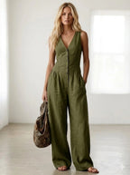 Driftly green V-neck wide-leg jumpsuit with front button closure and side pockets, linen-effect fabric, in a minimalist studio setting with soft window light.