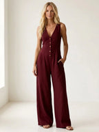 Driftly red V-neck wide-leg jumpsuit with front button closure and side pockets, linen-effect fabric, in a minimalist studio setting with soft window light.