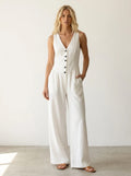 Driftly white V-neck wide-leg jumpsuit with front button closure and side pockets, linen-effect fabric, in a minimalist studio setting with soft window light.