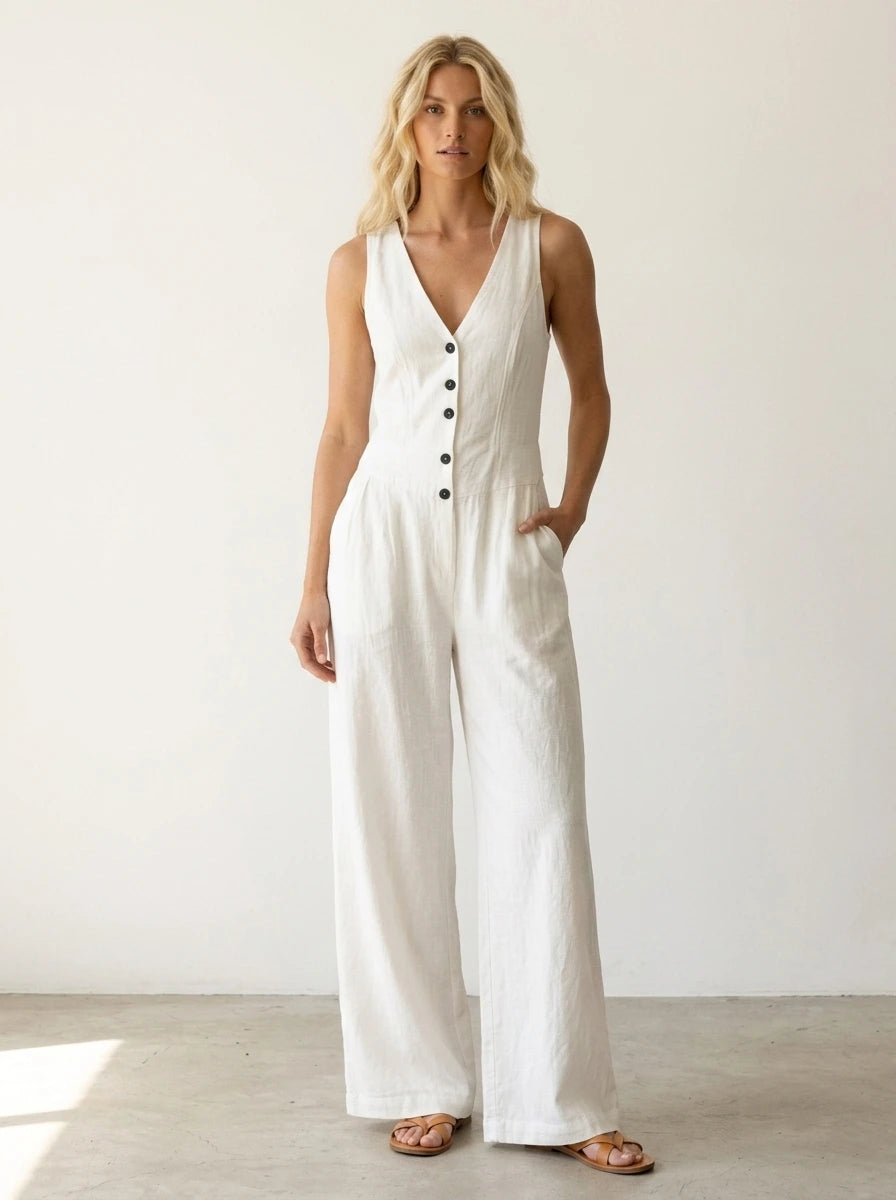 Driftly white V-neck wide-leg jumpsuit with front button closure and side pockets, linen-effect fabric, in a minimalist studio setting with soft window light.