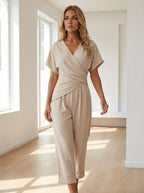 Woman wearing an apricot wrap V-neck jumpsuit in a bright minimalist interior