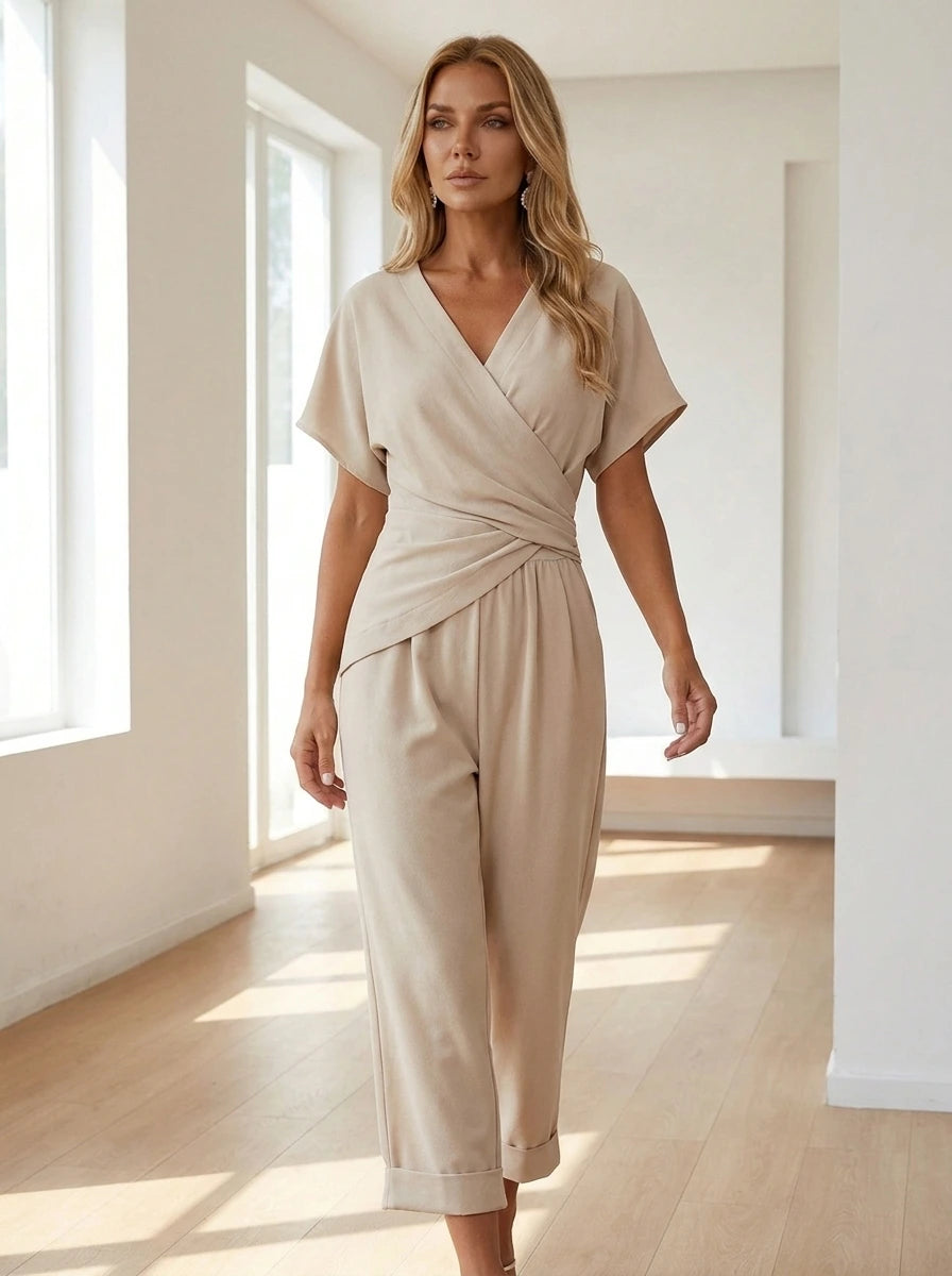 Woman wearing an apricot wrap V-neck jumpsuit in a bright minimalist interior