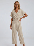 Woman wearing an apricot wrap V-neck jumpsuit with draped waist, studio shot