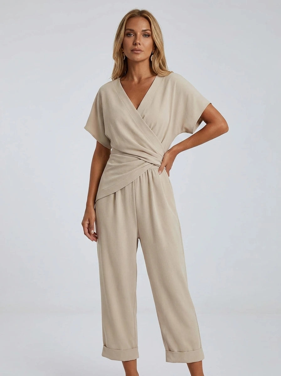 Woman wearing an apricot wrap V-neck jumpsuit with draped waist, studio shot