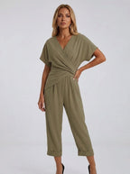 Woman wearing a khaki wrap V-neck jumpsuit with draped waist, studio shot