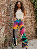 Woman wearing multicolor boho chic flared pants against a brick wall