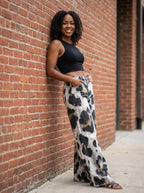 Woman wearing black-white cheetah print bohemian pants against a brick wall