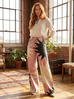 Woman wearing pink bohemian chic high-waisted patterned pants, standing in a sunlit loft