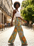 Woman wearing yellow floral print palazzo pants, walking on a cobblestone street