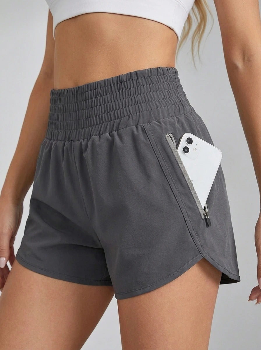 Close-up of gray running yoga shorts showing ruched waistband and zippered side pocket with phone.