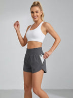 Gray high-waisted running yoga shorts with ruched waistband and zippered side pocket, studio front view.