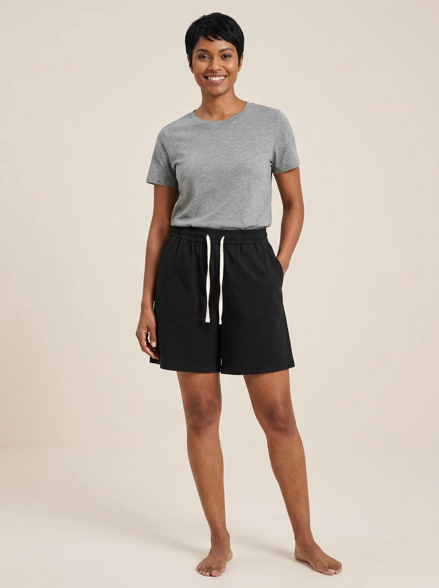 Black cotton wide-leg shorts with elastic waistband and white drawstring, studio front view.
