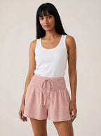 Pink high-waist drawstring shorts with shirred waistband, relaxed fit, studio front view.