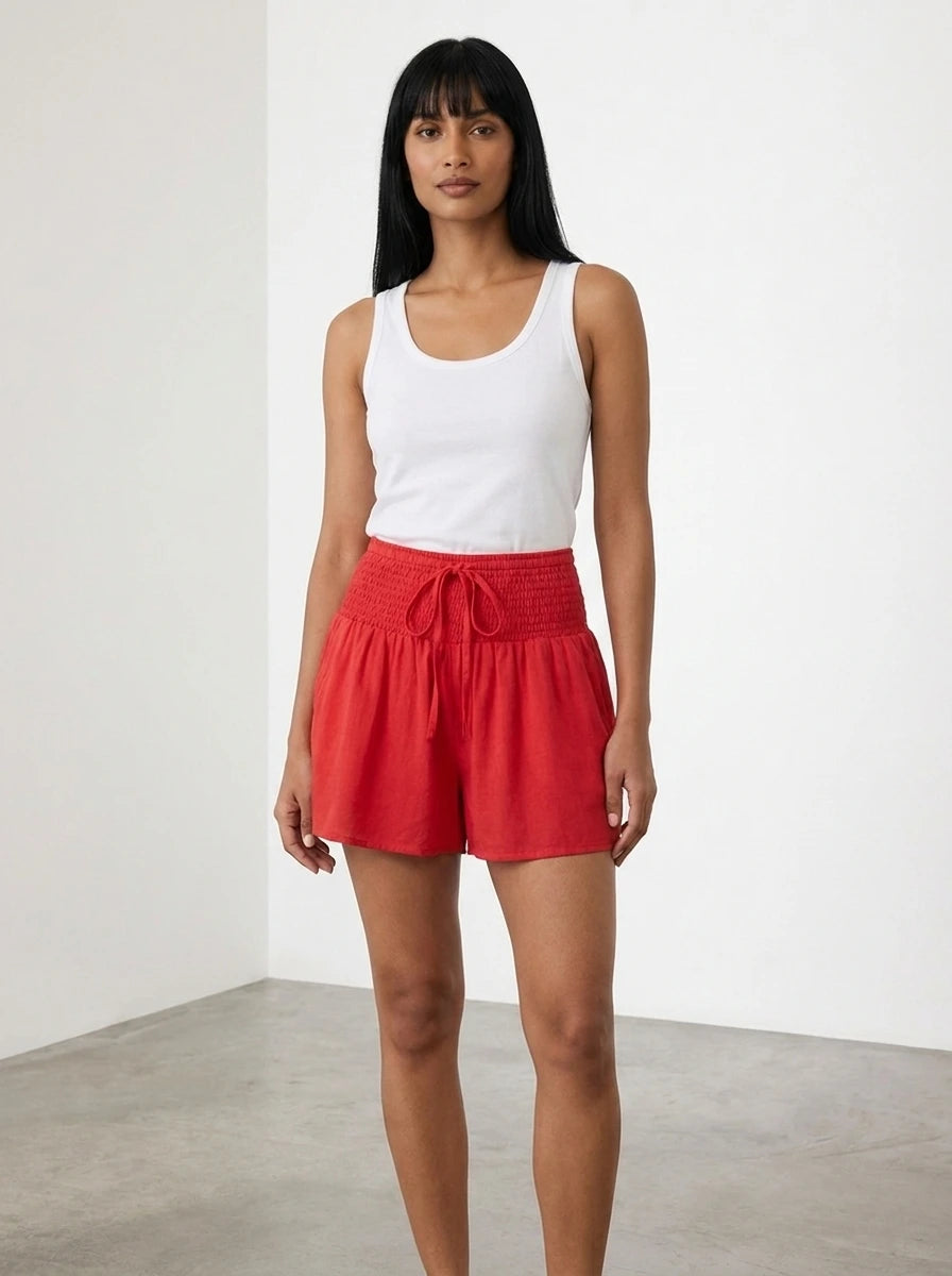 Red high-waist drawstring shorts with shirred waistband, relaxed fit, studio front view.