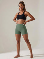 Green high-waisted yoga shorts, slim fit, soft stretchy fabric, studio front view.