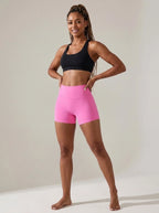 Pink high-waisted yoga shorts, slim fit, soft stretchy fabric, studio front view.