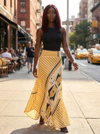 Woman wearing a yellow geometric print satin maxi skirt on a city street