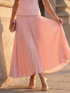 Woman wearing a pink structured bodice pleated skirt set - studio photo