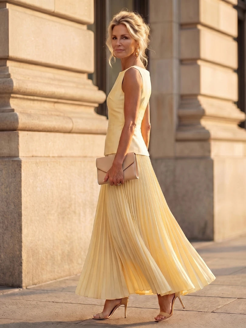 Woman wearing a yellow structured bodice pleated skirt set - studio photo
