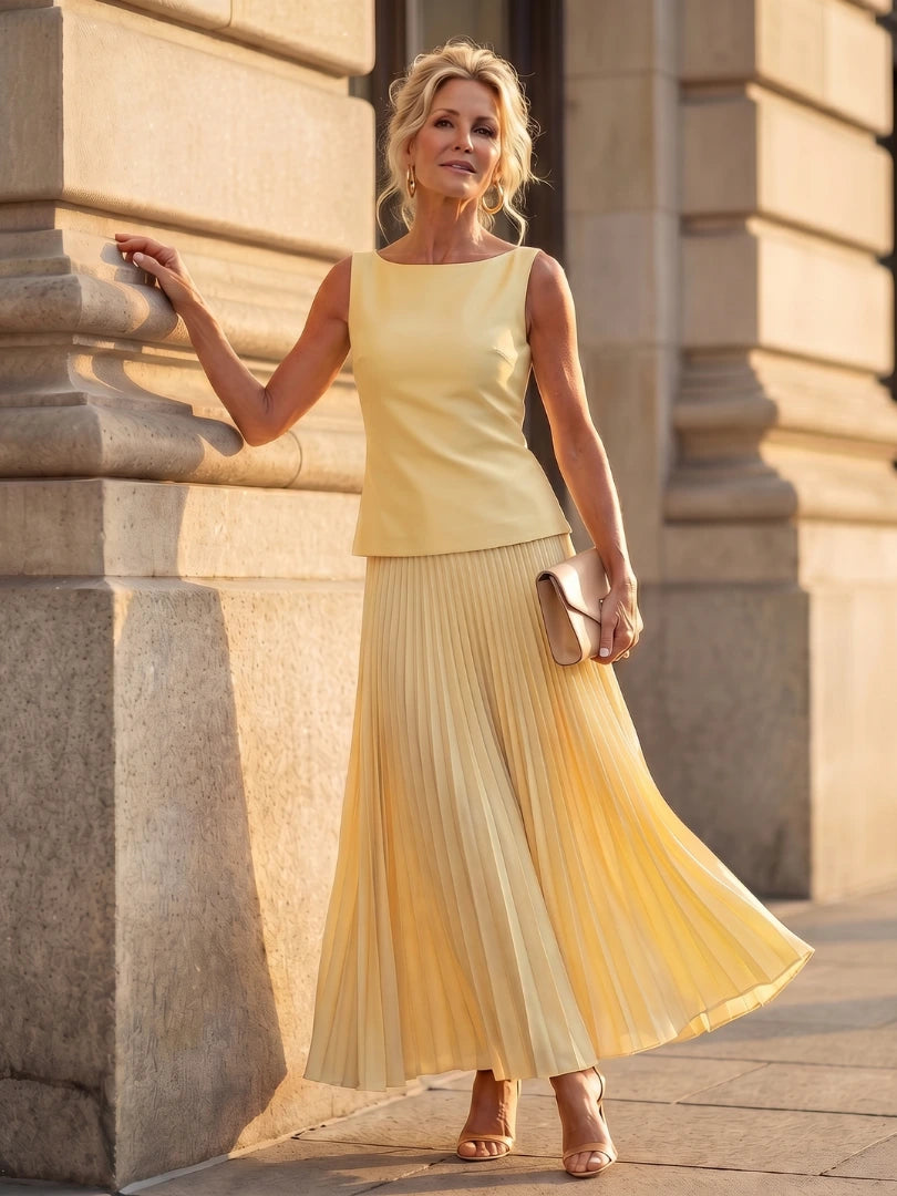 Woman wearing a yellow structured bodice pleated skirt set - studio photo