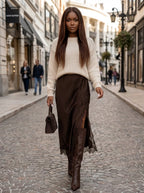 Woman wearing a chocolate brown viscose satin midi skirt with lace trim on a city street