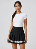 Woman wearing a black pleated mini skirt with white stripe hem in a studio setting