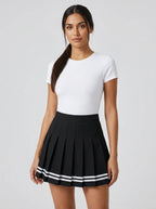 Woman wearing a black pleated mini skirt with white stripe hem in a studio setting