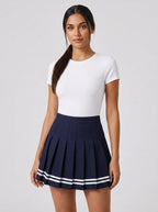 Woman wearing a navy pleated mini skirt with white stripe hem in a studio setting