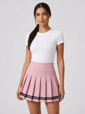 Woman wearing a pink pleated mini skirt with black stripe hem in a studio setting
