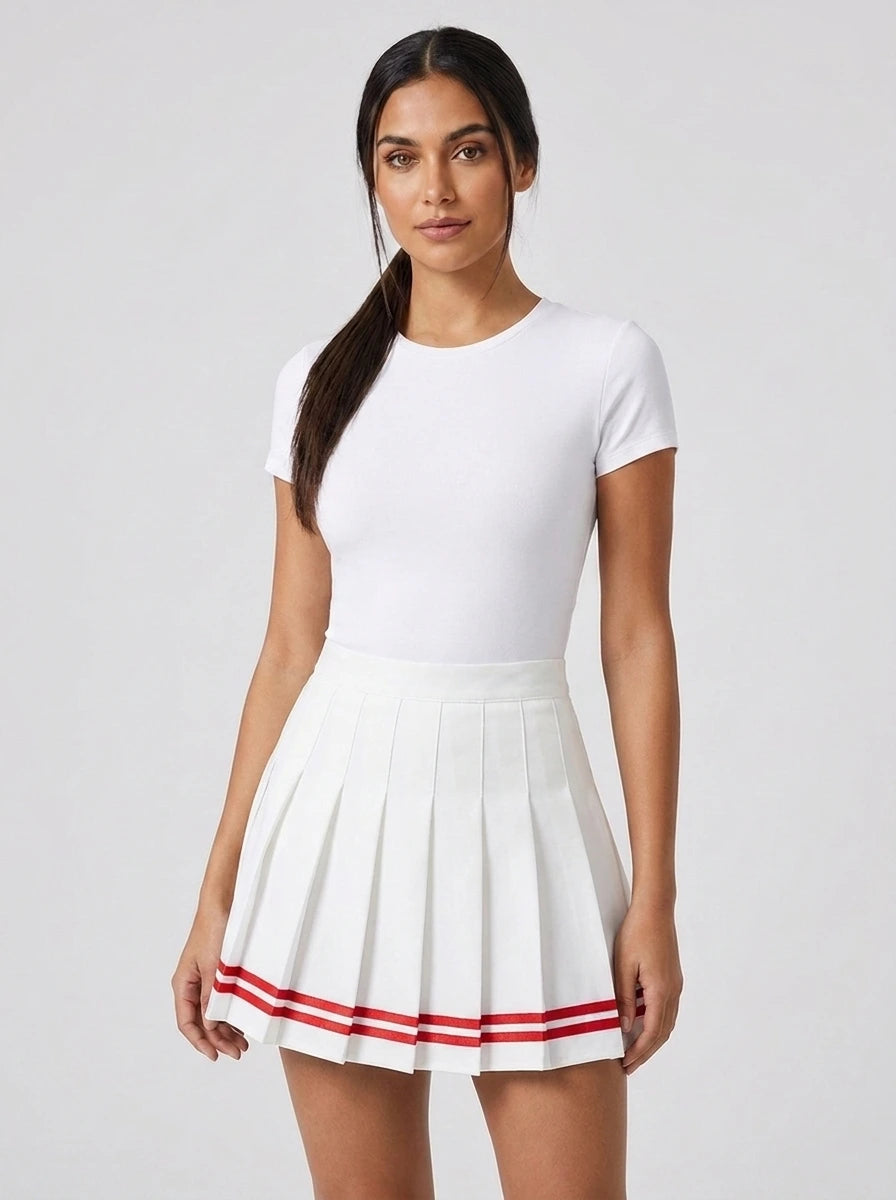 Woman wearing a white pleated mini skirt with red striped patchwork trim in a studio setting